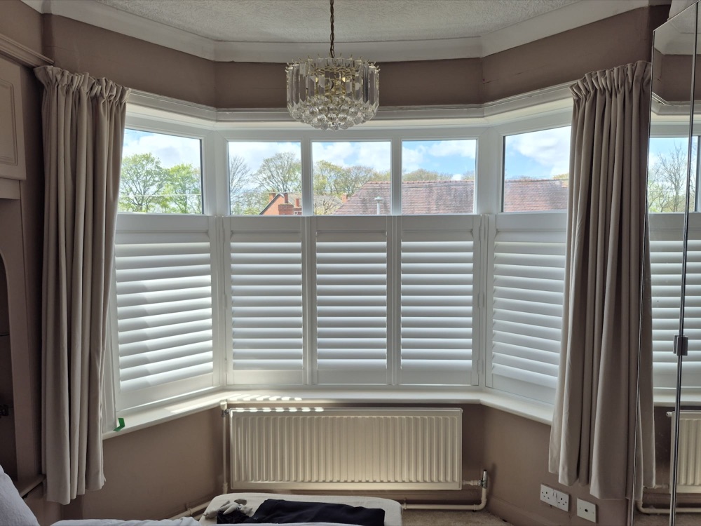 White café-style shutters fitted around a bay window